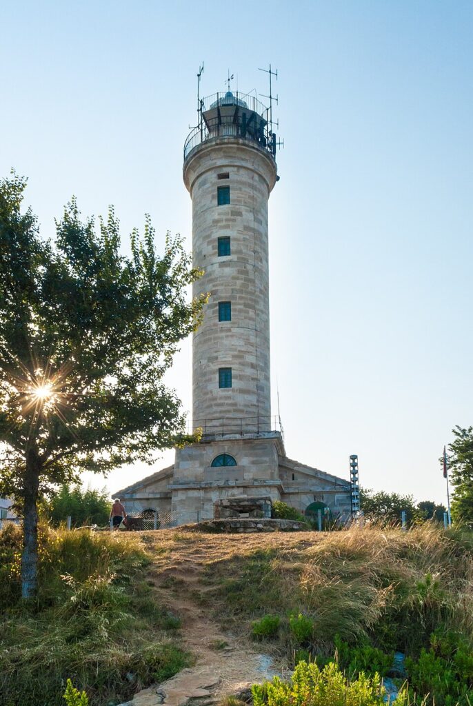 The historic Savudrija Lighthouse standing against a coastal landscape with clear skies.