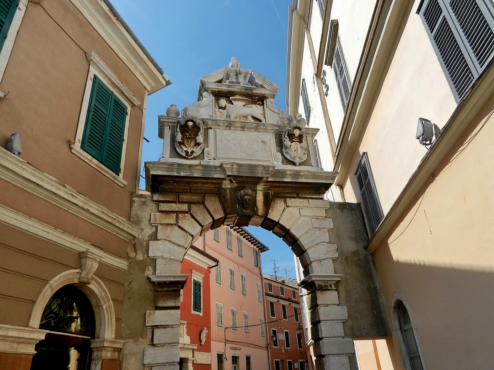 The historic Balbi Arch, a stone gateway leading into Rovinj's old town with visible clock tower and architectural details.